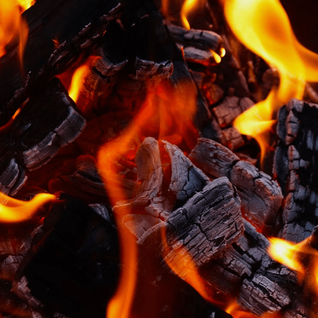 Glowing red-hot lumps of burning Namibian hardwood charcoal from Charcoal Bags on an open braai grid